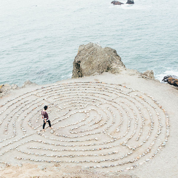 a maze on the sand and a person near the sea to represent "Diversity in Graphene" 2023